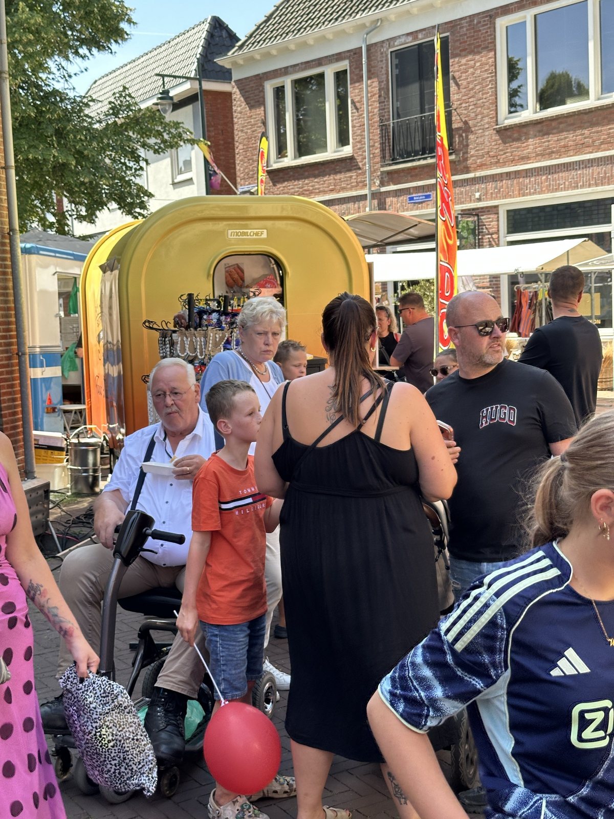 Bezoekers ontmoeten elkaar tussen marktkramen en een verkoopwagen